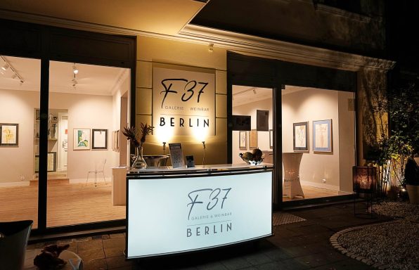 Moderne Galerie in Berlin mit beleuchtetem Empfangstresen und großen Fensterfronten.