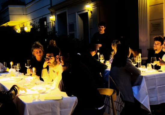 Elegante Restaurantatmosphäre mit Gästen an beleuchteten Tischen im Freien.